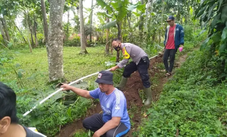 Bhabinkamtibmas Sarampad Gotong Royong Bareng Warga Pasang Pipa di Sukawarna