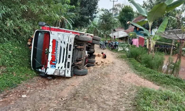 Jalan Rusak, Truk Bermuatan Kayu Terguling di Desa Gelaranyar Cianjur