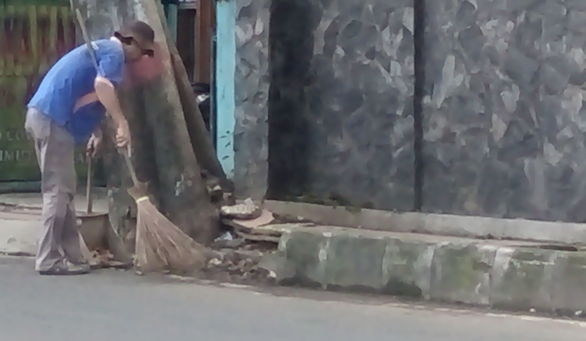 Seorang petugas sedang menyapu jalan agar terlihat bersih.