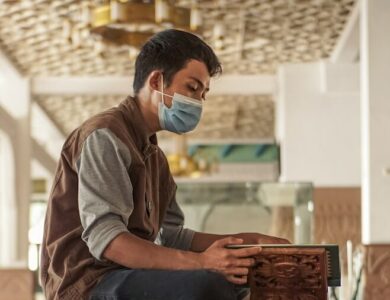 man in gray hoodie and blue pants sitting on brown wooden table