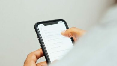 man in white top holding iPhone