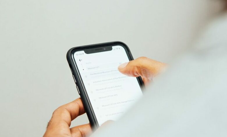 man in white top holding iPhone