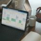 Three people in a meeting at a table discussing schedule on their Microsoft laptop