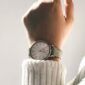 person wearing round silver-colored analog watch