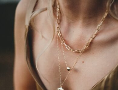 woman in gold sleeveless dress wearing gold necklace