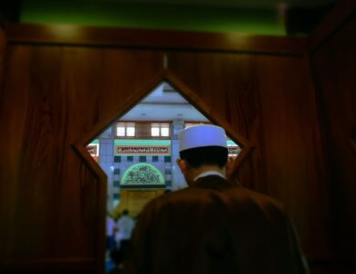 man in black coat standing near brown wooden door