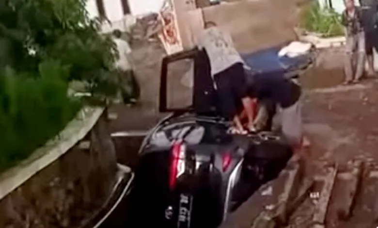 Sebuah mobil SUV hitam terperosok ke parit di Cugenang, Cianjur, diduga karena pengemudi mengantuk saat hendak parkir.