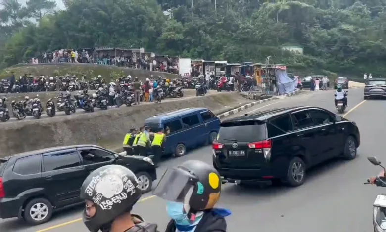 Sebuah mobil gagal menanjak di Jalur Puncak Bogor saat one way. Enam polisi sigap membantu mendorong hingga mobil kembali berjalan.