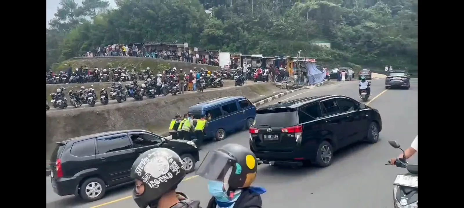 Sebuah mobil gagal menanjak di Jalur Puncak Bogor saat one way. Enam polisi sigap membantu mendorong hingga mobil kembali berjalan.