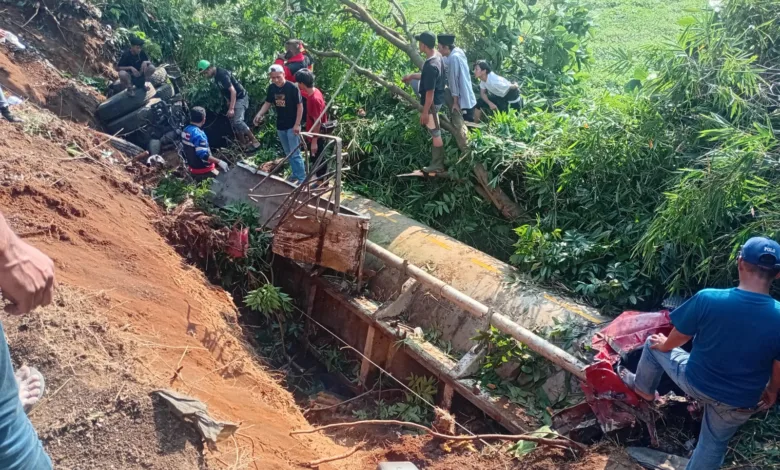 KECELAKAAN MAUT: Warga dan petugas melihat kondisi truk tangki pengangkut air yang ringsek setelah terguling ke jurang di Jalan Raya Gekbrong-Sukabumi, Cianjur, Senin (9/6/2025). Kecelakaan yang diduga akibat rem blong ini menewaskan dua orang dan membuat proses evakuasi badan truk menjadi sulit karena posisinya yang curam. (Foto: Fauzi/Cianjurupdate)