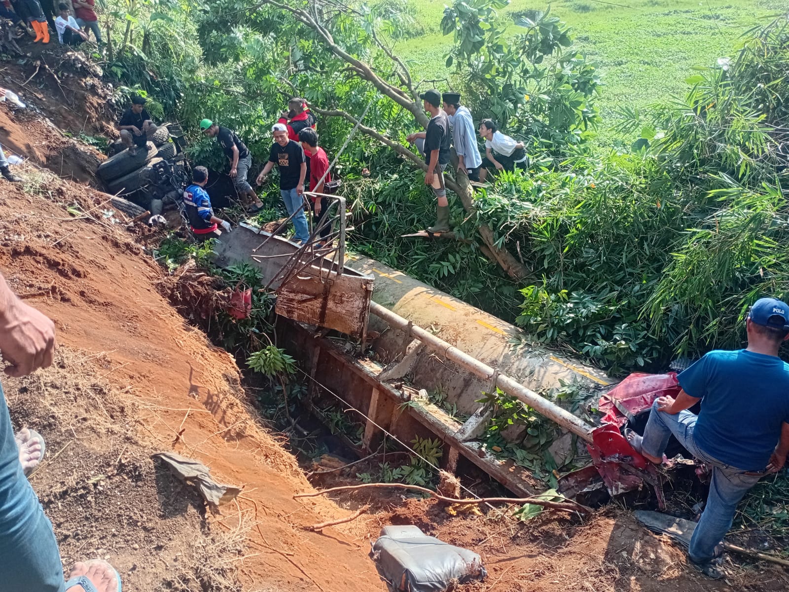 KECELAKAAN MAUT: Warga dan petugas melihat kondisi truk tangki pengangkut air yang ringsek setelah terguling ke jurang di Jalan Raya Gekbrong-Sukabumi, Cianjur, Senin (9/6/2025). Kecelakaan yang diduga akibat rem blong ini menewaskan dua orang dan membuat proses evakuasi badan truk menjadi sulit karena posisinya yang curam. (Foto: Fauzi/Cianjurupdate)