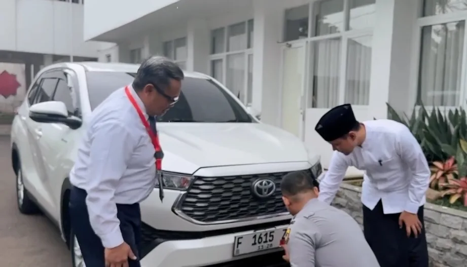 Bupati Cianjur dr. Mohammad Wahyu Ferdian (kanan) mengamati petugas Dishub (jongkok) saat memasang stiker program parkir berlangganan pada kendaraannya
