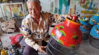 WARISAN KEAHLIAN: Didin Jaenudin, pengrajin di Desa Sindangasih, memperlihatkan sangkar burung lukis hasil karyanya. Keterampilan yang diwarisi sejak era 60-an ini terus bertahan dan menjadi penopang utama ekonomi warga setempat. (Foto: Fauzi/Cianjurupdate)