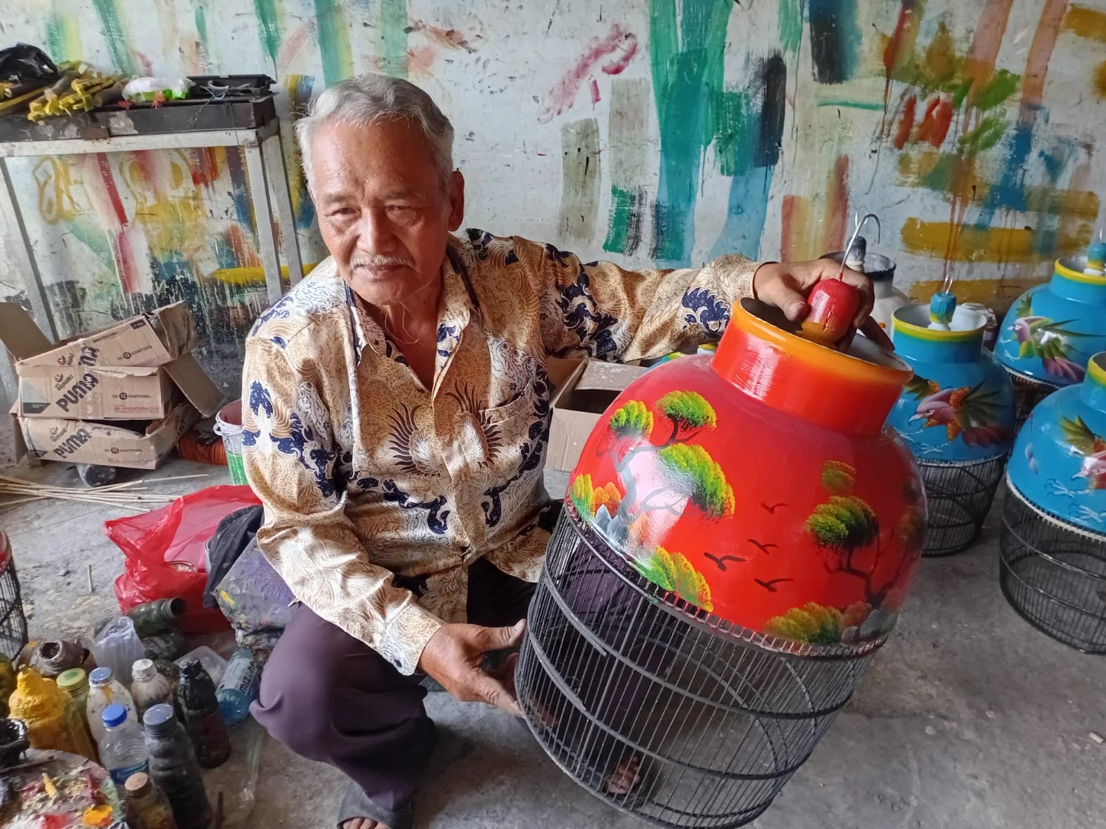 WARISAN KEAHLIAN: Didin Jaenudin, pengrajin di Desa Sindangasih, memperlihatkan sangkar burung lukis hasil karyanya. Keterampilan yang diwarisi sejak era 60-an ini terus bertahan dan menjadi penopang utama ekonomi warga setempat. (Foto: Fauzi/Cianjurupdate)