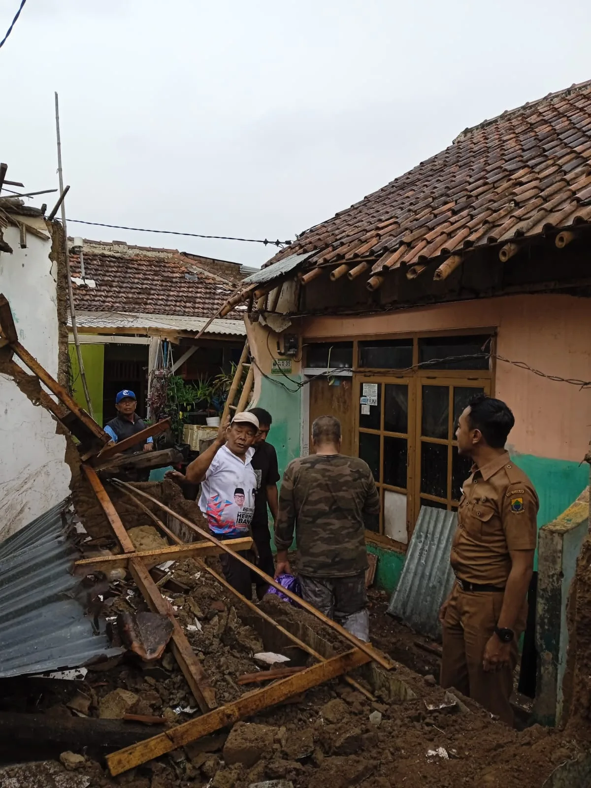 Aparat kelurahan (kanan) bersama warga memeriksa puing-puing bangunan rumah yang rusak berat akibat terjangan angin kencang di Kelurahan Sayang, Kecamatan Cianjur, Senin (3/11/2025).