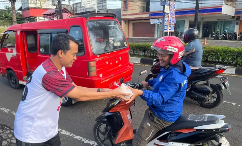 Manager PLN UP3 Cianjur menyerahkan paket sarapan gratis kepada salah seorang pengendara ojek sebagai bagian dari program "Berbagi Saling Menguatkan" di Cianjur.