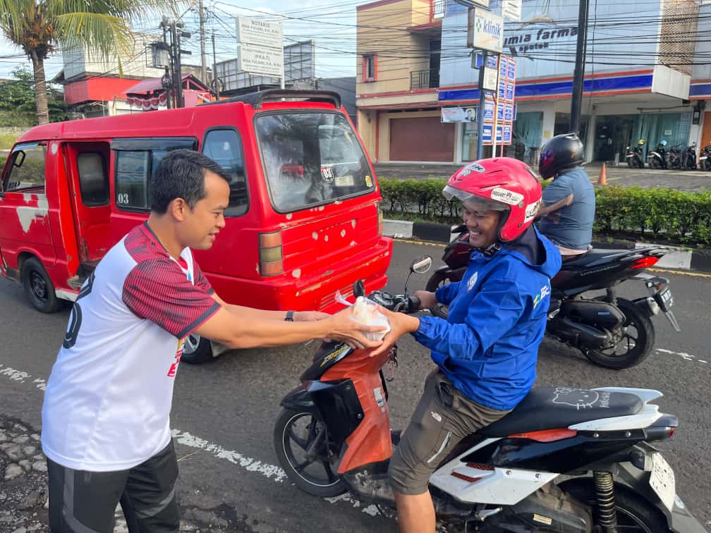 Manager PLN UP3 Cianjur menyerahkan paket sarapan gratis kepada salah seorang pengendara ojek sebagai bagian dari program "Berbagi Saling Menguatkan" di Cianjur.