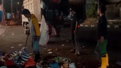 Sejumlah petugas kebersihan berjibaku mengangkut tumpukan sampah dari TPS sementara ke dalam truk pada malam hari di Cianjur.