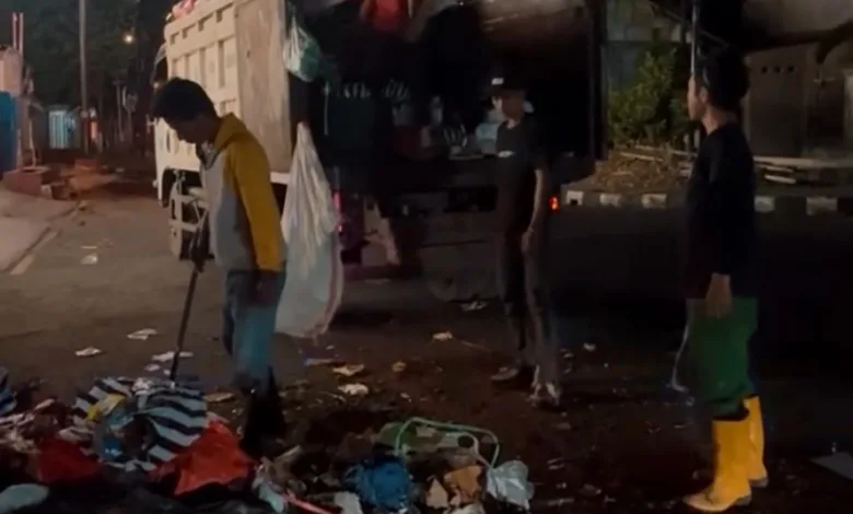 Sejumlah petugas kebersihan berjibaku mengangkut tumpukan sampah dari TPS sementara ke dalam truk pada malam hari di Cianjur.