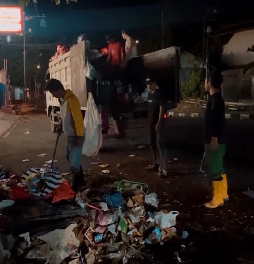 Sejumlah petugas kebersihan berjibaku mengangkut tumpukan sampah dari TPS sementara ke dalam truk pada malam hari di Cianjur.