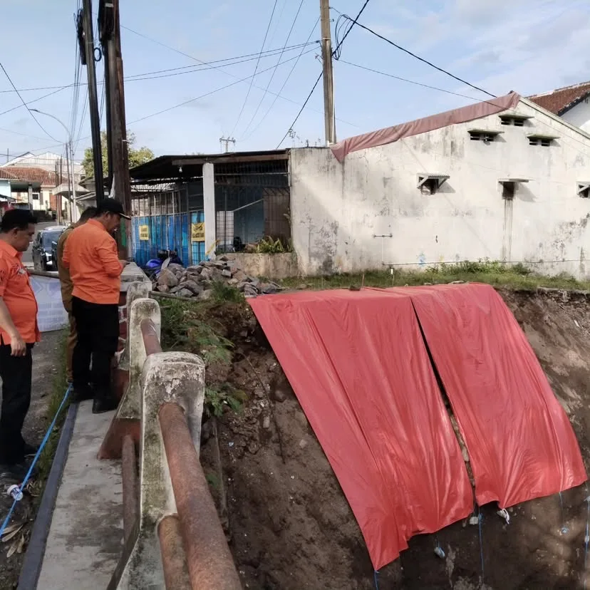 Jajaran BPBD mengamati area longsoran sayap Jembatan Cianjur Girang yang telah ditutup terpal sebagai penanganan darurat pasca-cuaca ekstrem, Senin (24/11).