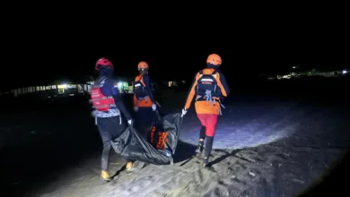 Petugas tim SAR gabungan menggotong kantong jenazah saat melakukan penyisiran dan evakuasi di area pantai pada malam hari.