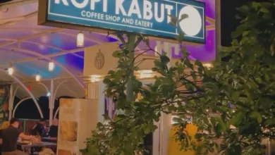 SUASANA malam di Kopi Kabut Coffee Shop and Eatery. Papan nama kafe yang menyala terang menyambut pengunjung yang tengah menikmati waktu bersantai.