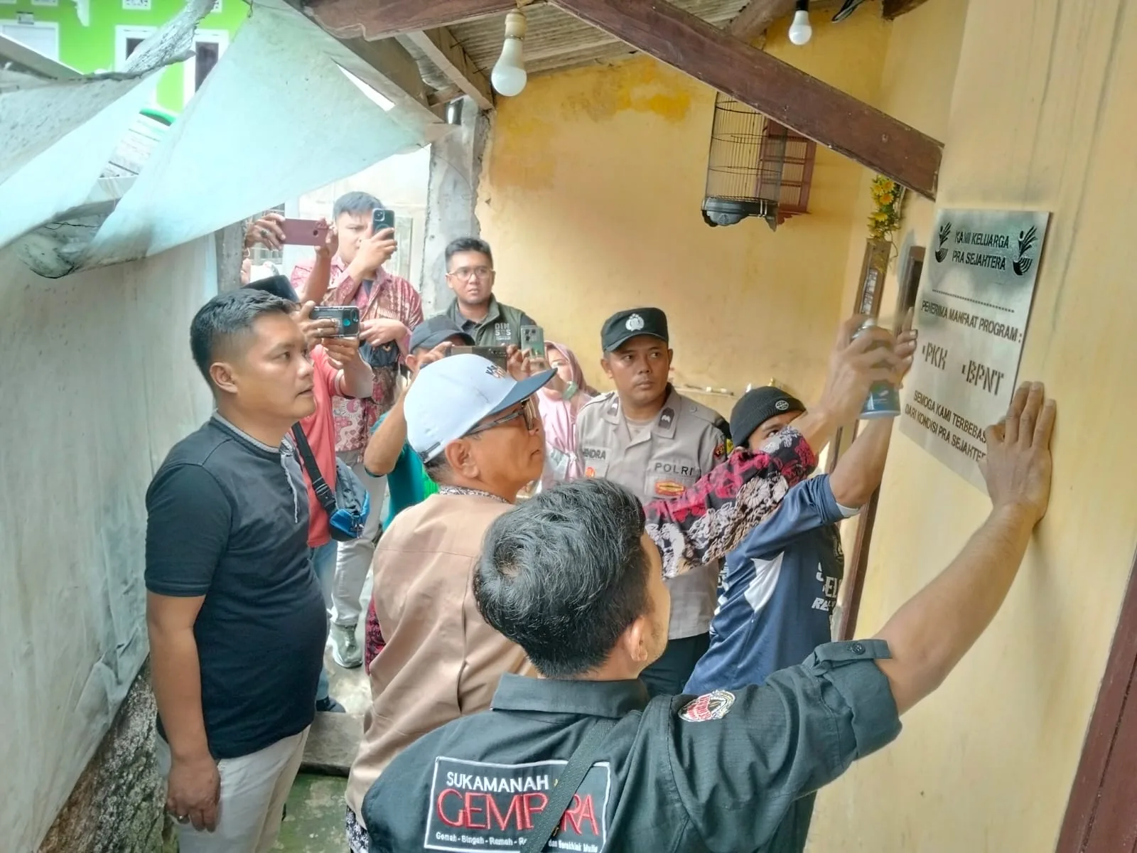 Petugas menempelkan plakat penanda "Keluarga Pra Sejahtera" di salah satu rumah Keluarga Penerima Manfaat (KPM) di Desa Sukamanah, Kecamatan Cugenang, Cianjur, Kamis (18/12/2025).