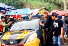 Mobil patroli Polsek Pacet saat mengevakuasi juru parkir berinisial E (30) dari kepungan warga di Rest Area Segar Alam, Puncak, Cianjur, Sabtu (27/12/2025).