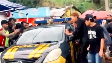 Mobil patroli Polsek Pacet saat mengevakuasi juru parkir berinisial E (30) dari kepungan warga di Rest Area Segar Alam, Puncak, Cianjur, Sabtu (27/12/2025).