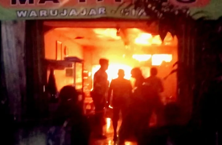 Api berkobar di Warung Nasi Ma Titing, Warujajar. Petugas dan warga terlihat di lokasi kejadian saat kebakaran terjadi pada malam hari.
