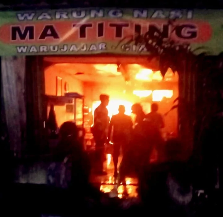 Api berkobar di Warung Nasi Ma Titing, Warujajar. Petugas dan warga terlihat di lokasi kejadian saat kebakaran terjadi pada malam hari.