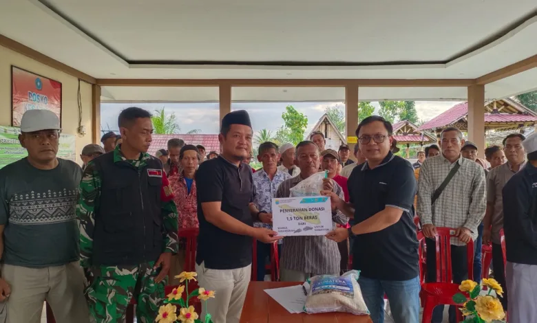 Kepala Desa Sukamanah, Indra Surya Pradana (kiri), menyerahkan secara simbolis donasi 1,5 ton beras kepada Pimpinan Cianjur Update, Indra Arfiandi (kanan), disaksikan oleh Babinsa dan unsur RT/RW di Aula Agro Edu Wisata Tani Arta Sukamanah, Sabtu (13/12/2025).