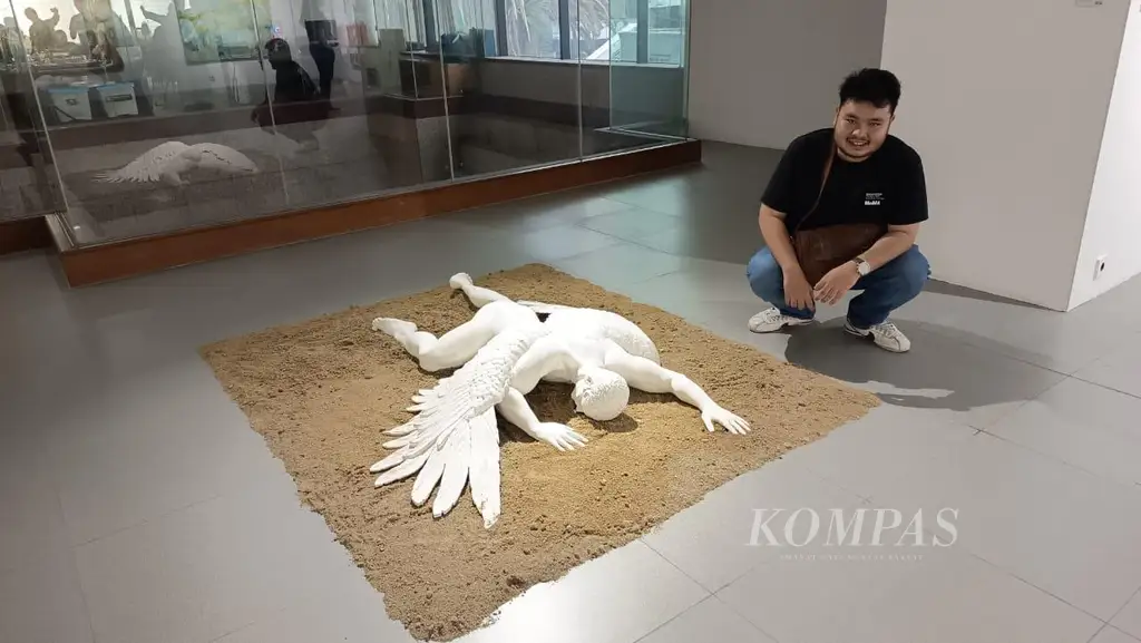Seniman Alexander Chris asal Cianjur, Jawa Barat, dengan karya patung ”Fall of Icarus”, Sabtu (29/11/2025), di Neo Gallery, Jakarta