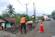 Sejumlah pekerja mengenakan rompi keselamatan saat memperbaiki titik jalan yang rusak di jalur Sukabumi Selatan