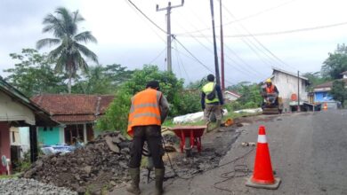 Sejumlah pekerja mengenakan rompi keselamatan saat memperbaiki titik jalan yang rusak di jalur Sukabumi Selatan